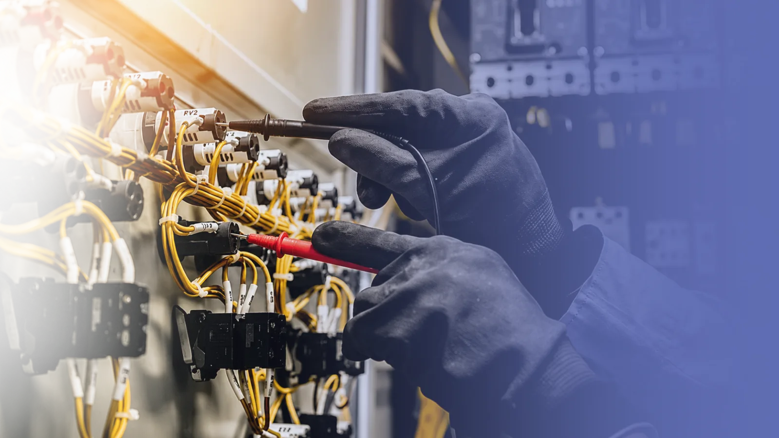 Electrician testing wiring on an industrial electrical panel